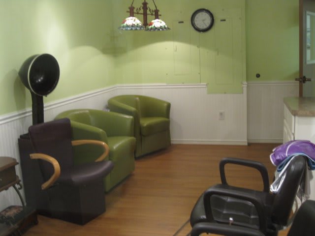 A waiting area in a hair salon with green walls and comfortable seating.