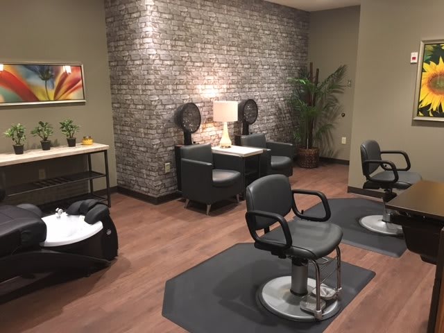 A modern hair salon with stylish chairs and a brick accent wall.