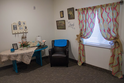 A cozy corner of a living room featuring a comfortable chair, a colorful table, and decorative elements.