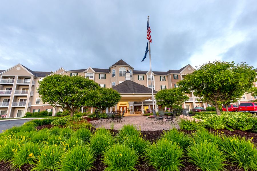 A front view of a hotel with a flagpole and landscaped garden.