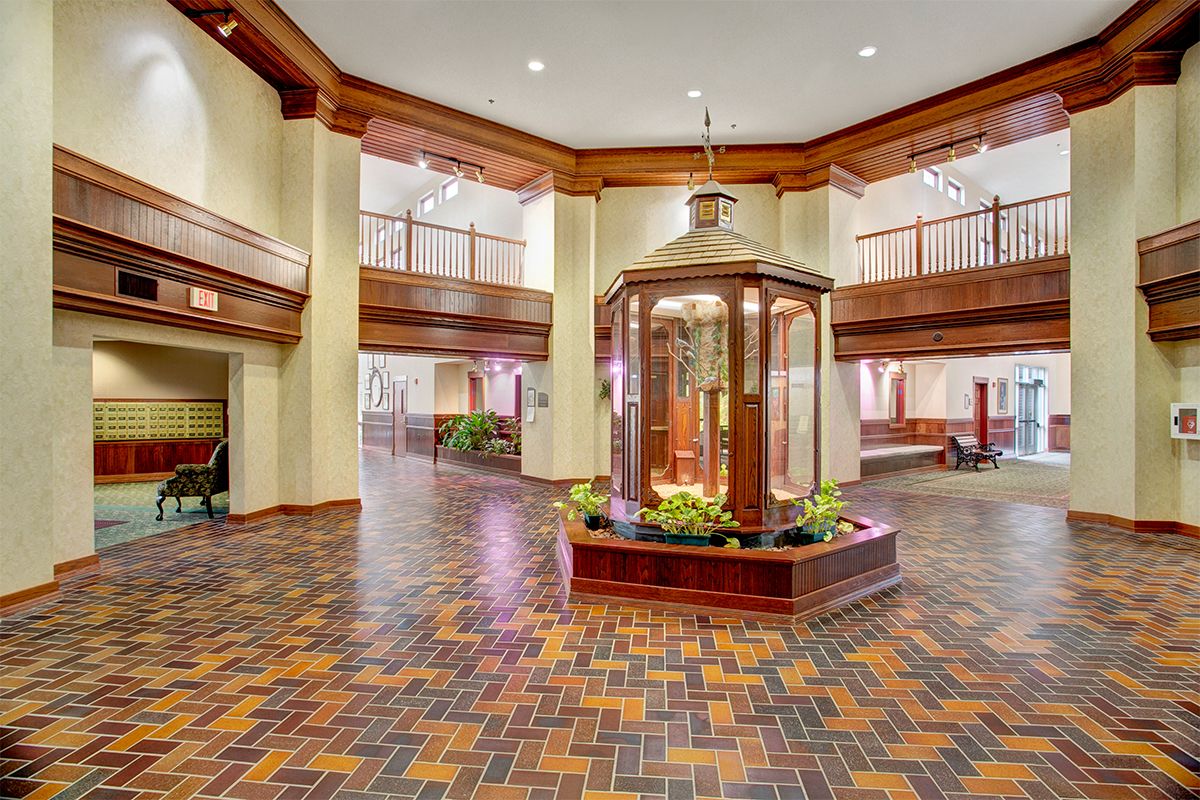A spacious lobby with wooden accents, featuring a central fountain and decorative plants.