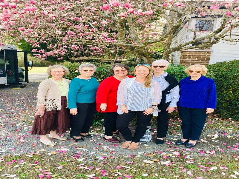 A group of people standing together under a blooming tree.