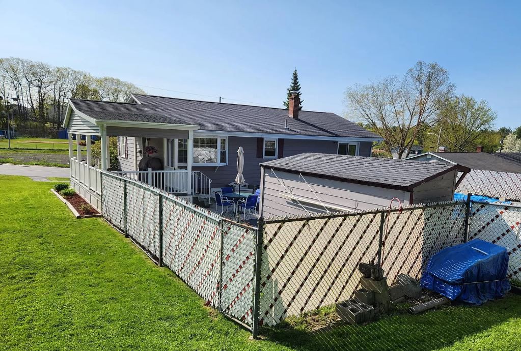A suburban house with a fenced backyard and lawn.
