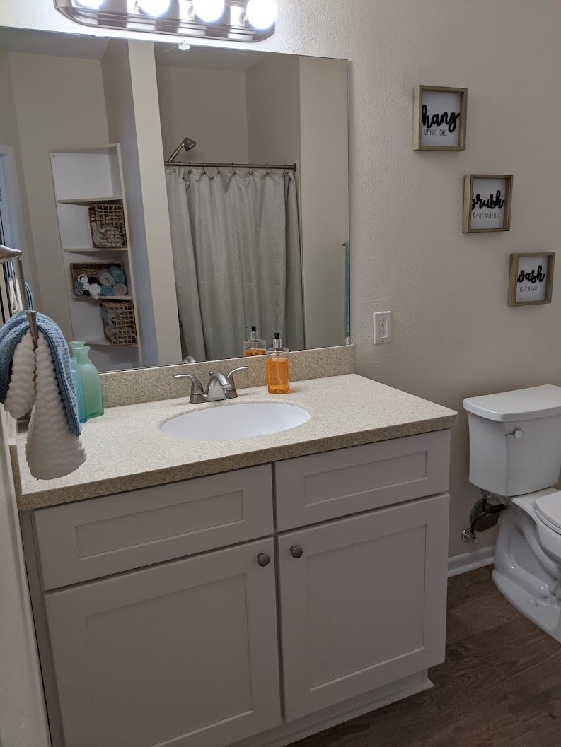 A clean and organized bathroom featuring a sink, mirror, and decor.