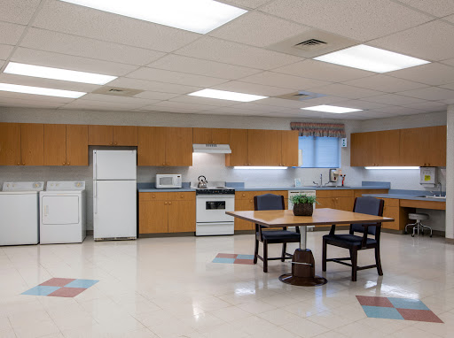 A modern kitchen space featuring wooden cabinetry, a dining table with chairs, and essential appliances.