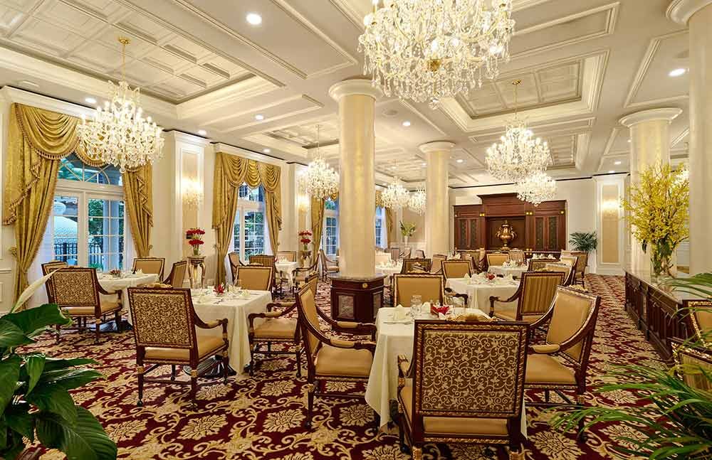 An elegant dining room with chandeliers and classic decor, featuring beautifully set tables in a luxurious setting.