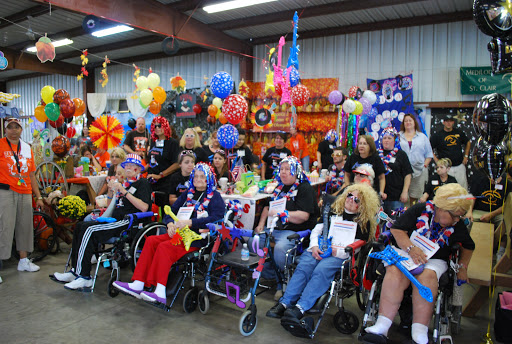 A joyful gathering of individuals in wheelchairs, celebrating together in a colorful decorated venue.