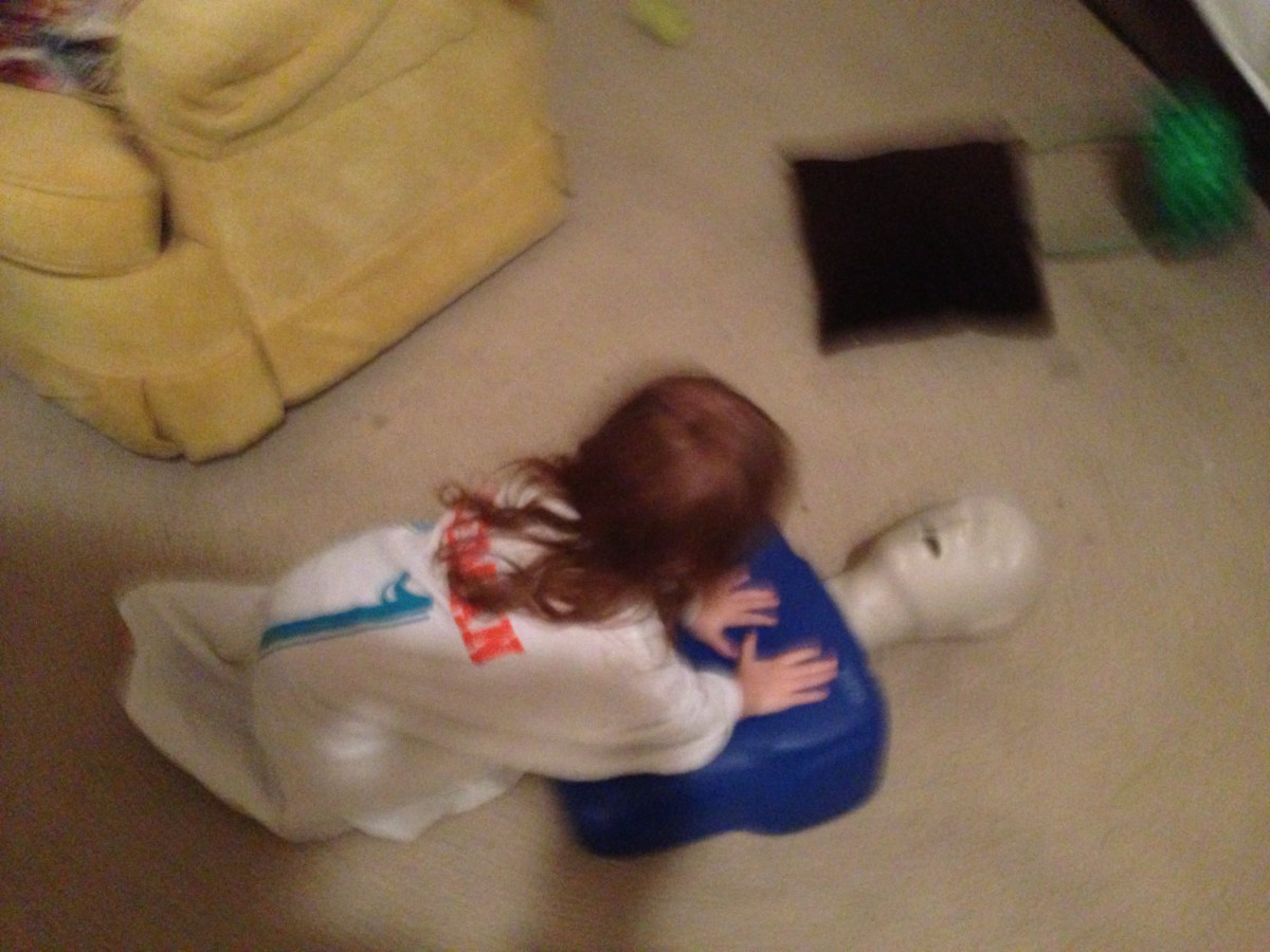 A child practicing CPR on a manikin indoors.
