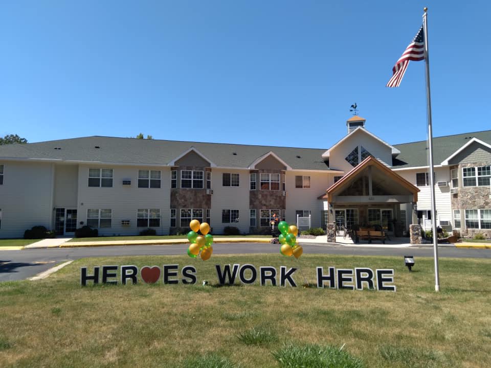 A building with a sign reading 'HEROES WORK HERE' and balloons on the lawn.