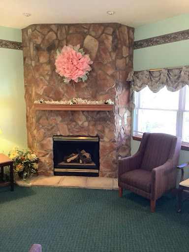 A cozy living room featuring a stone fireplace, floral decor, and a comfortable armchair.