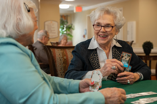 Two seniors enjoy a cheerful game of cards together, sharing smiles and laughter.