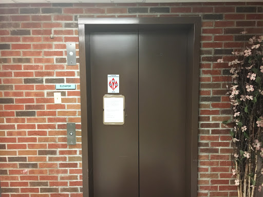 An elevator with closed doors in a brick-walled corridor.