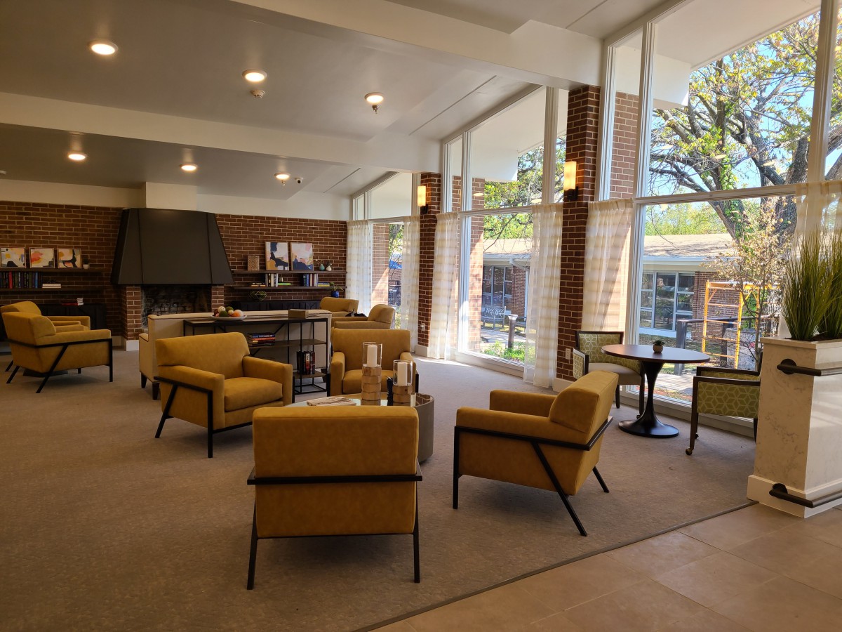 A modern lounge area with yellow chairs and large windows allowing natural light to fill the room.