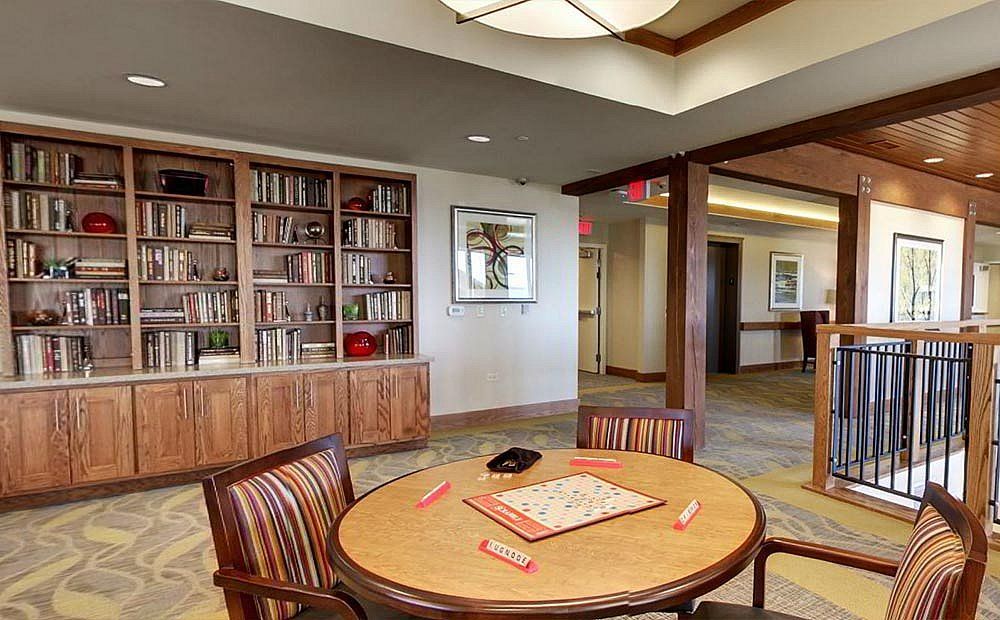 A cozy library interior with a round table set for board games and bookshelves in the background.
