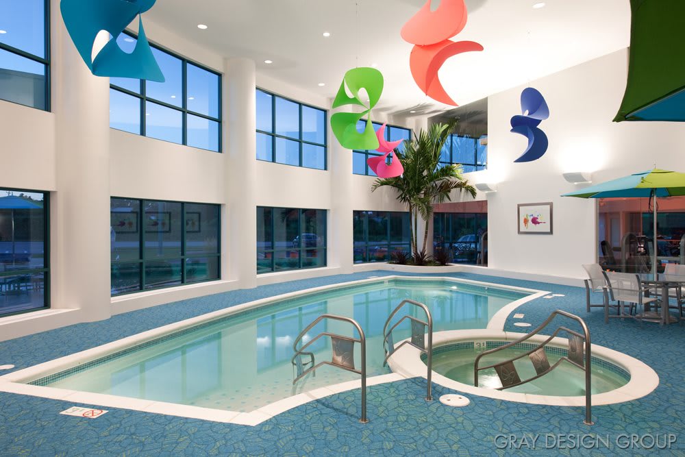 A modern indoor swimming pool with colorful decor and large windows.