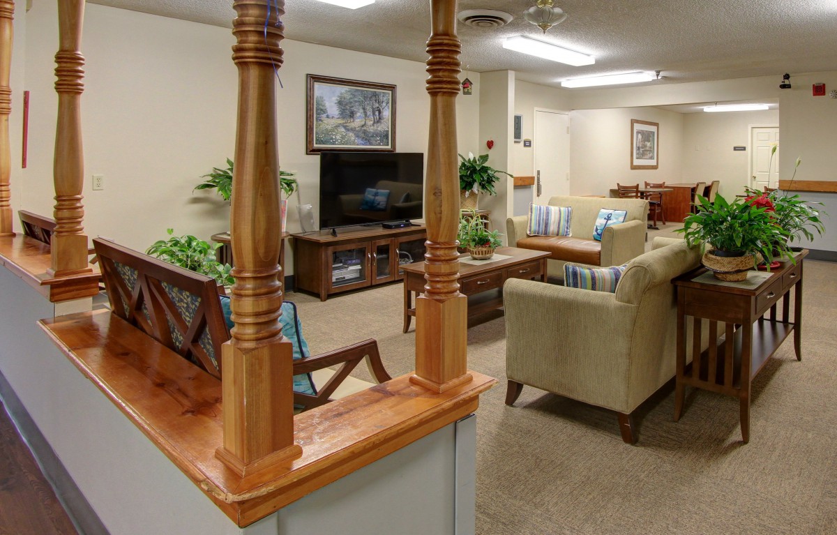 A cozy living room featuring a television, sofas, and wooden accents.