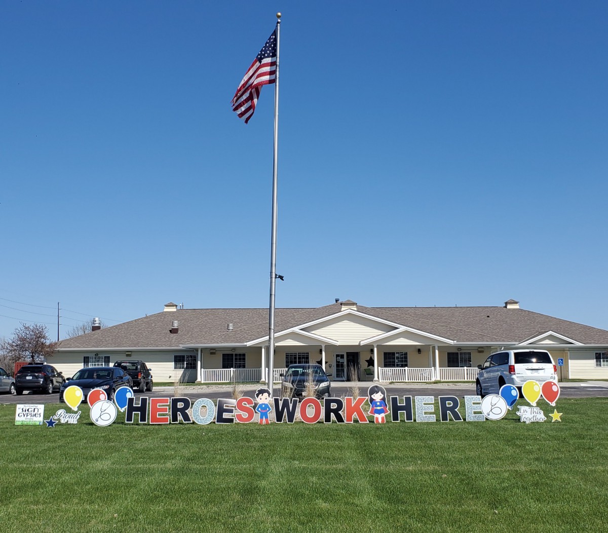A building with an American flag and a decorative sign on the lawn.