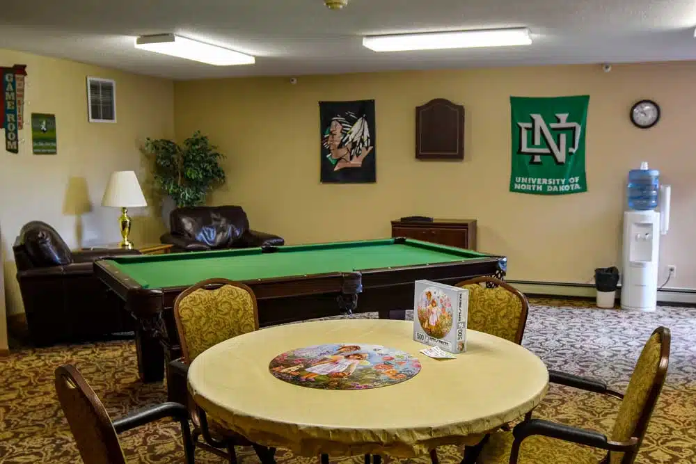 A cozy game room featuring a pool table and a round table with a puzzle in progress.
