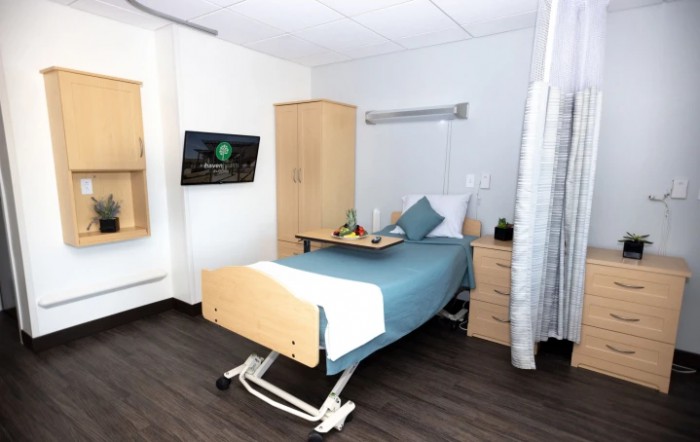 A modern hospital room with a single bed and essential furnishings.