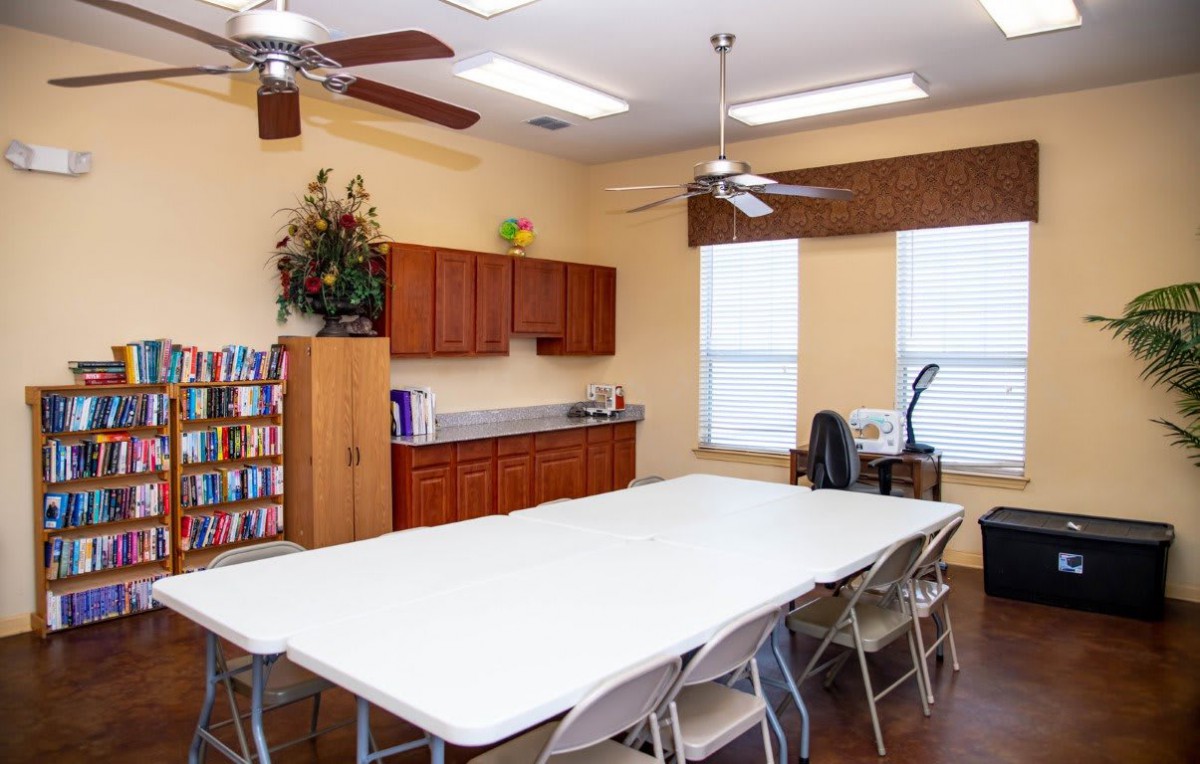A well-organized conference room with a large table, chairs, cabinets, and a bookshelf.