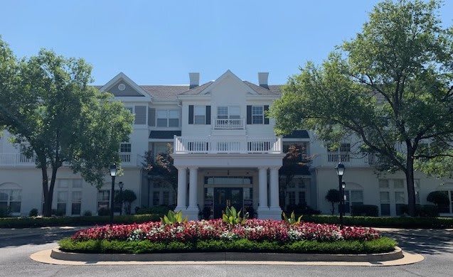 A large building with a grand entrance, surrounded by well-maintained landscaping and vibrant flowers.