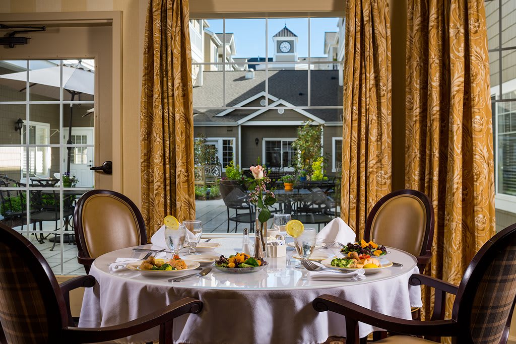 A beautifully set dining table by a window with an elegant outdoor view.