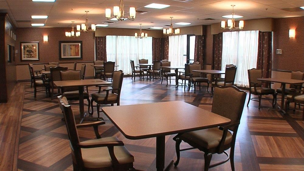 A spacious dining area with arranged tables and chairs, illuminated by overhead lights.
