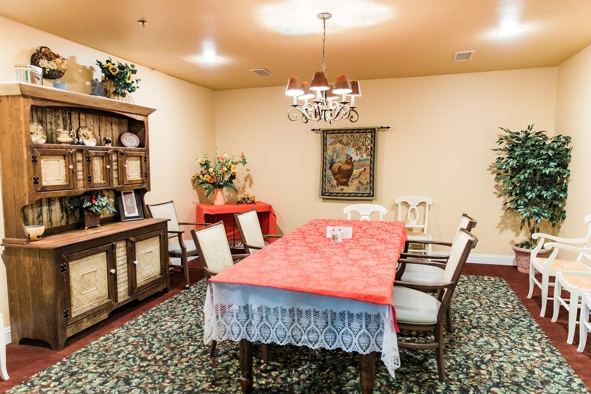 A cozy dining room with a red tablecloth, surrounded by chairs and adorned with a chandelier.