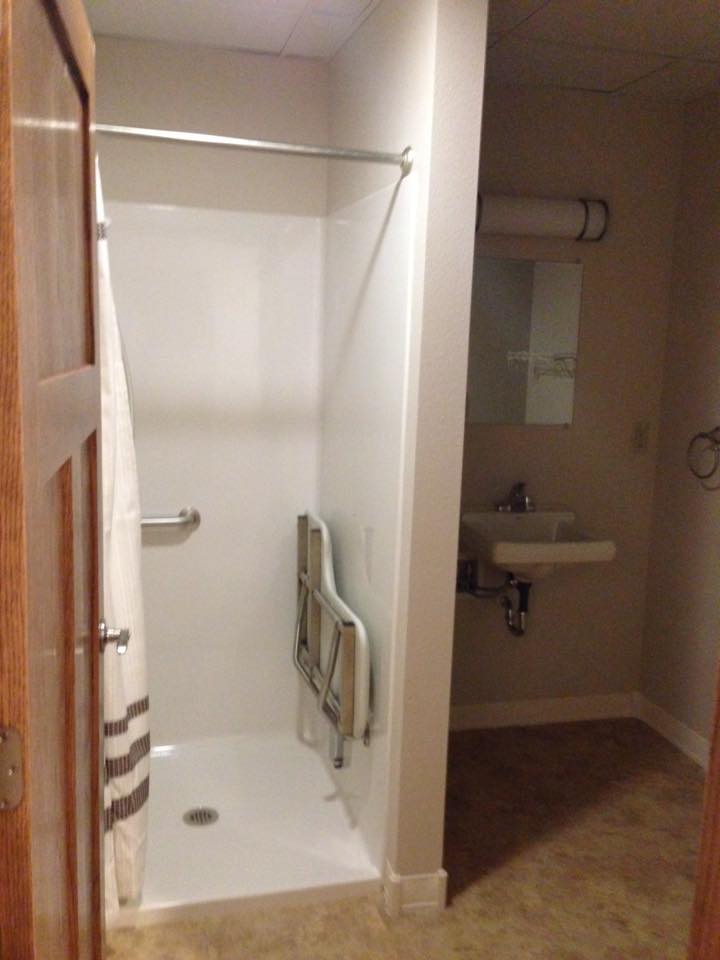 A bathroom with an accessible shower and sink area.
