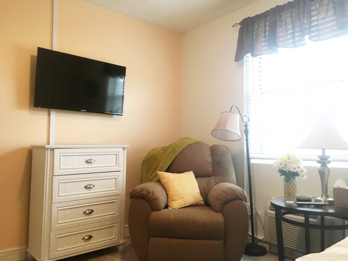 A cozy living room corner with an armchair, television, and dresser.