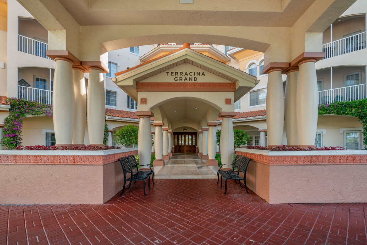 A covered entrance with columns and benches leading to a building.