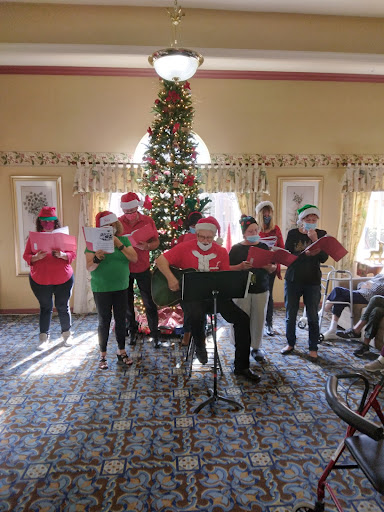 A joyful group singing Christmas carols in festive attire, surrounded by holiday decorations.