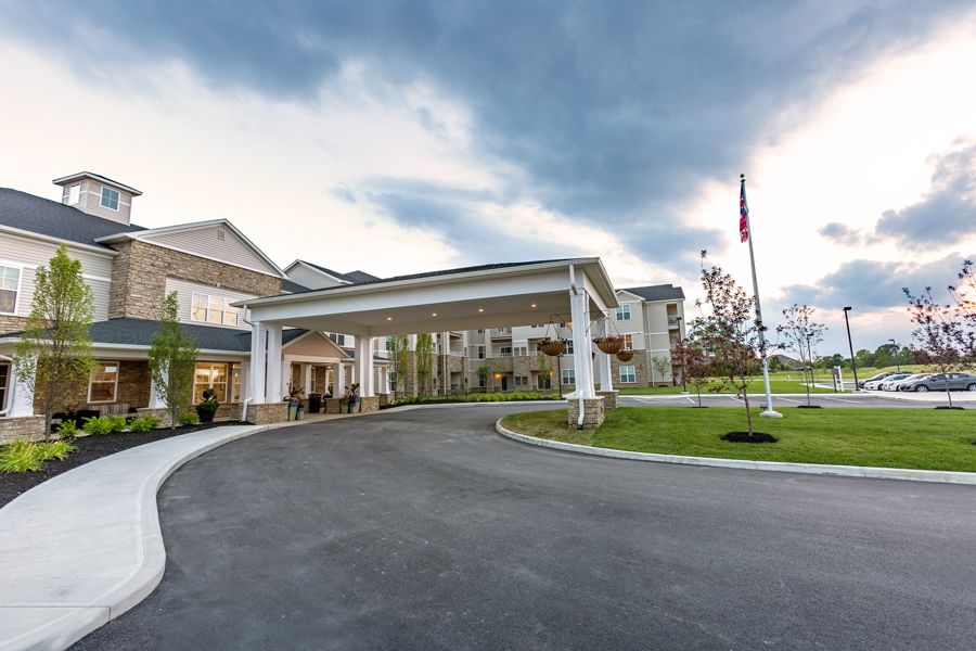 A large building with a prominent entrance and driveway, set against a cloudy sky.