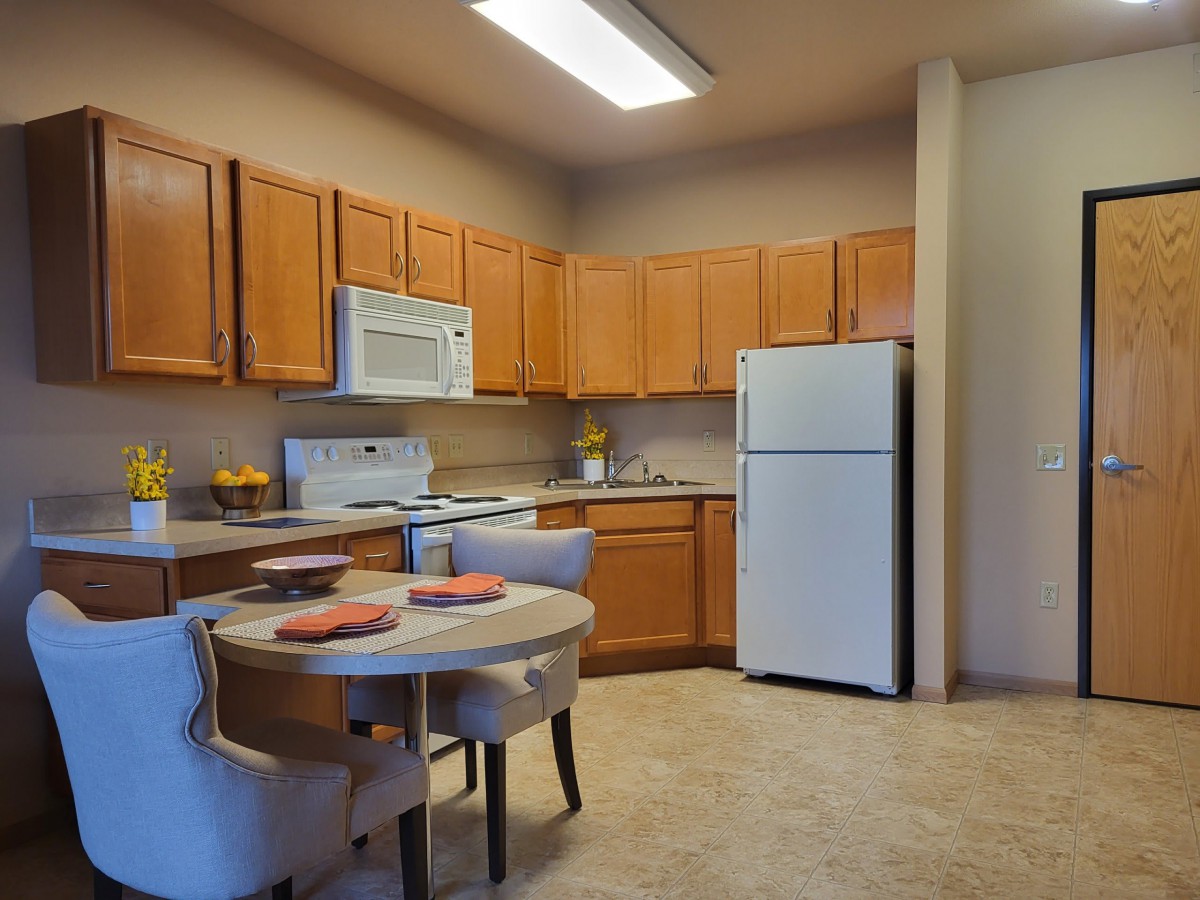 A modern kitchen with wooden cabinets and a small dining area.