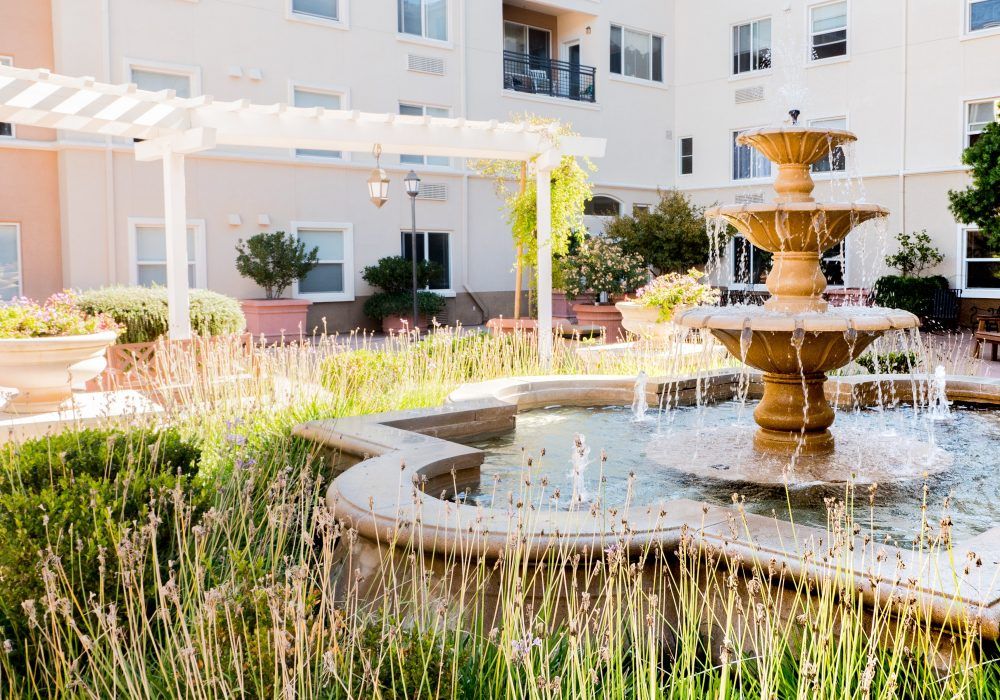 A beautiful outdoor fountain surrounded by greenery in an apartment complex courtyard.