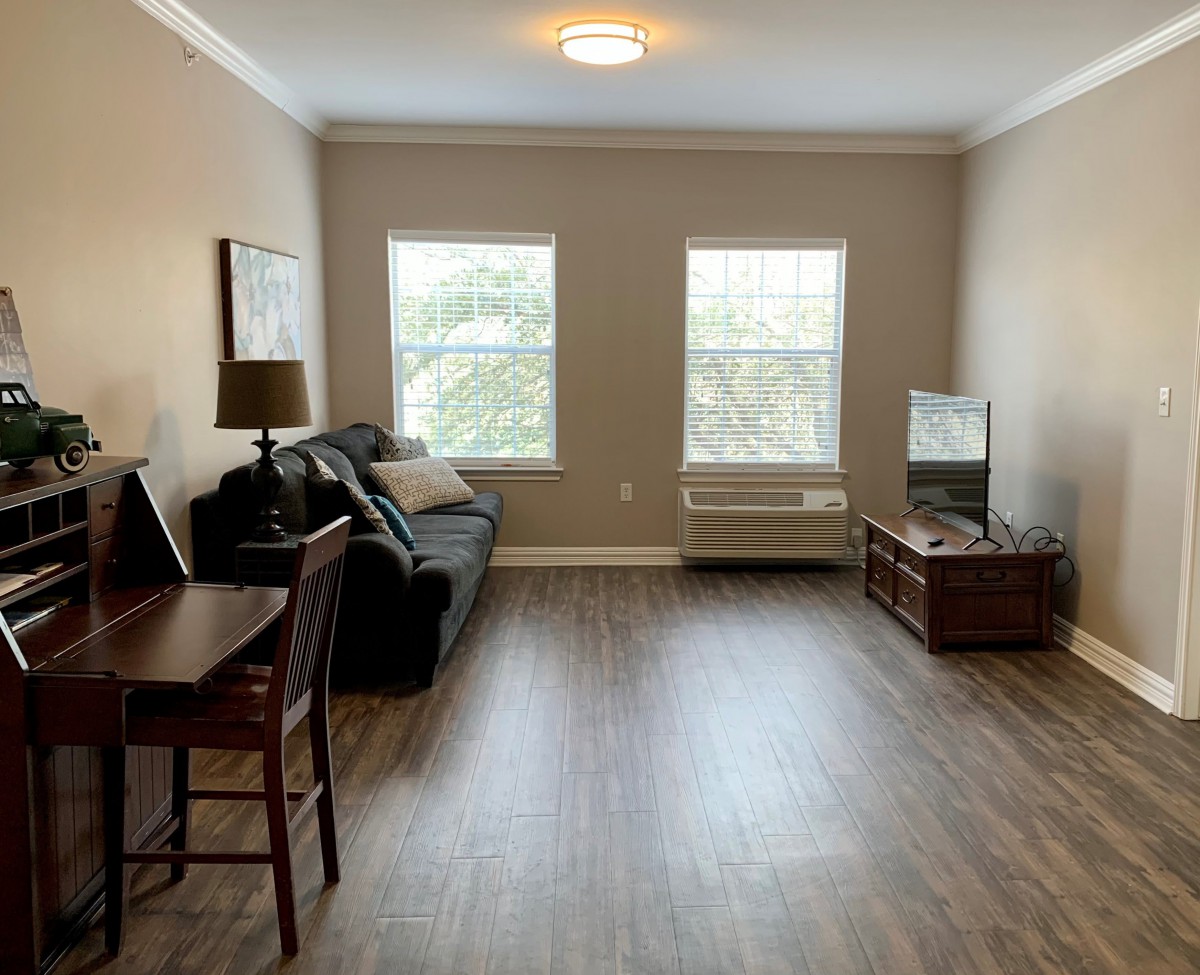 A cozy living room with a sofa, television, and wood flooring.