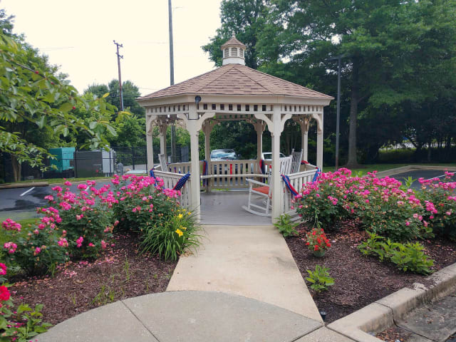 A charming gazebo surrounded by vibrant flowers in a peaceful park setting.