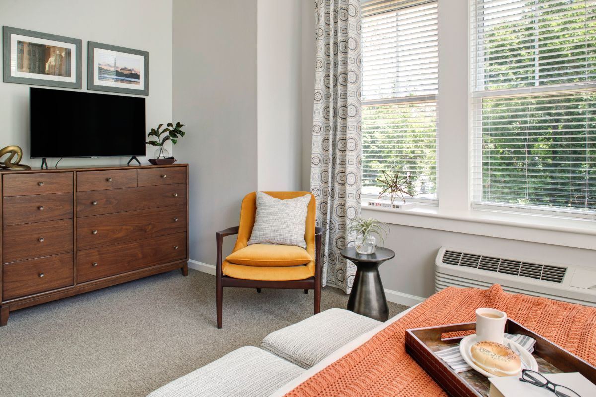 A modern living room with a bright yellow chair, television, and stylish decor.