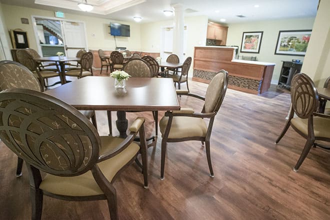 A spacious and modern dining area featuring elegant furniture with a wooden table and cushioned chairs.