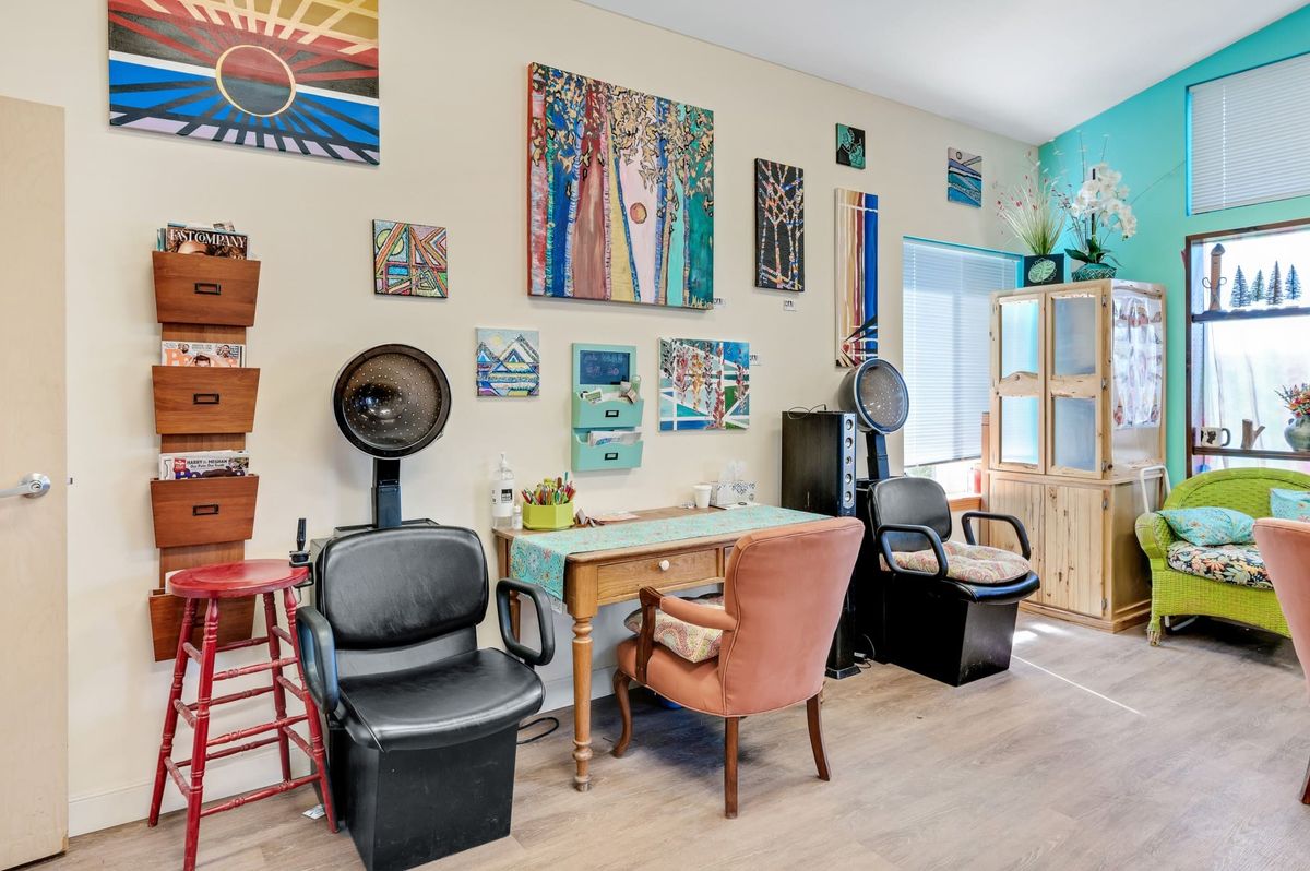 A cozy hair salon with vintage decor and colorful artwork adorning the walls.