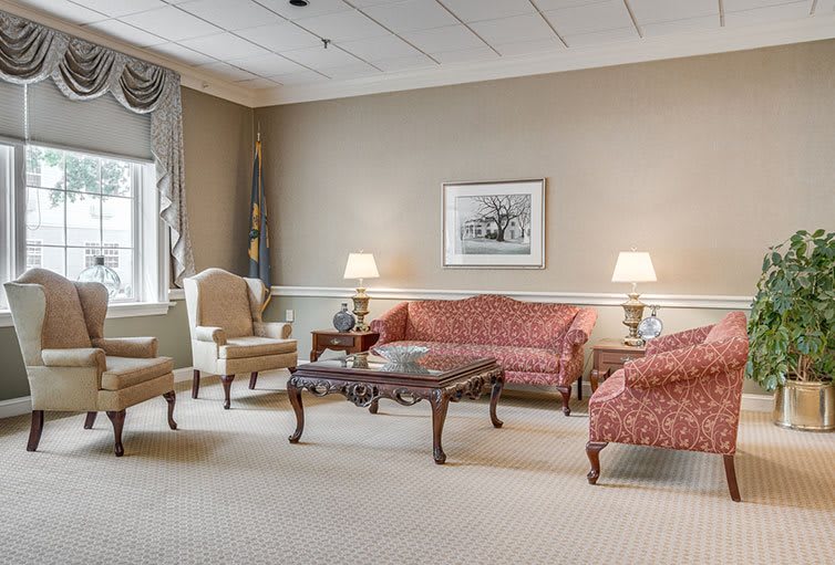 A traditional living room featuring elegant furniture, including a sofa, chairs, a wooden coffee table, and lamps.
