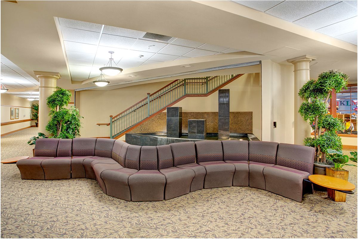 A modern lobby featuring a curvy sofa with a staircase in the background.