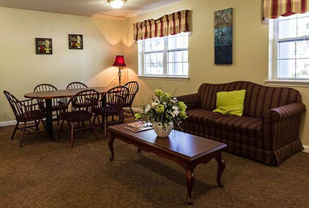 A cozy living room with a dining area, featuring a sofa, coffee table, and a dining set next to a window.