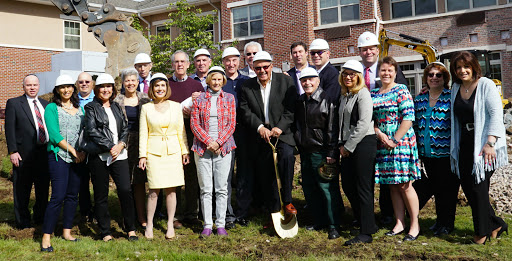 A group of community leaders gathered for a groundbreaking ceremony, wearing hard hats and celebrating the start of a new construction project.
