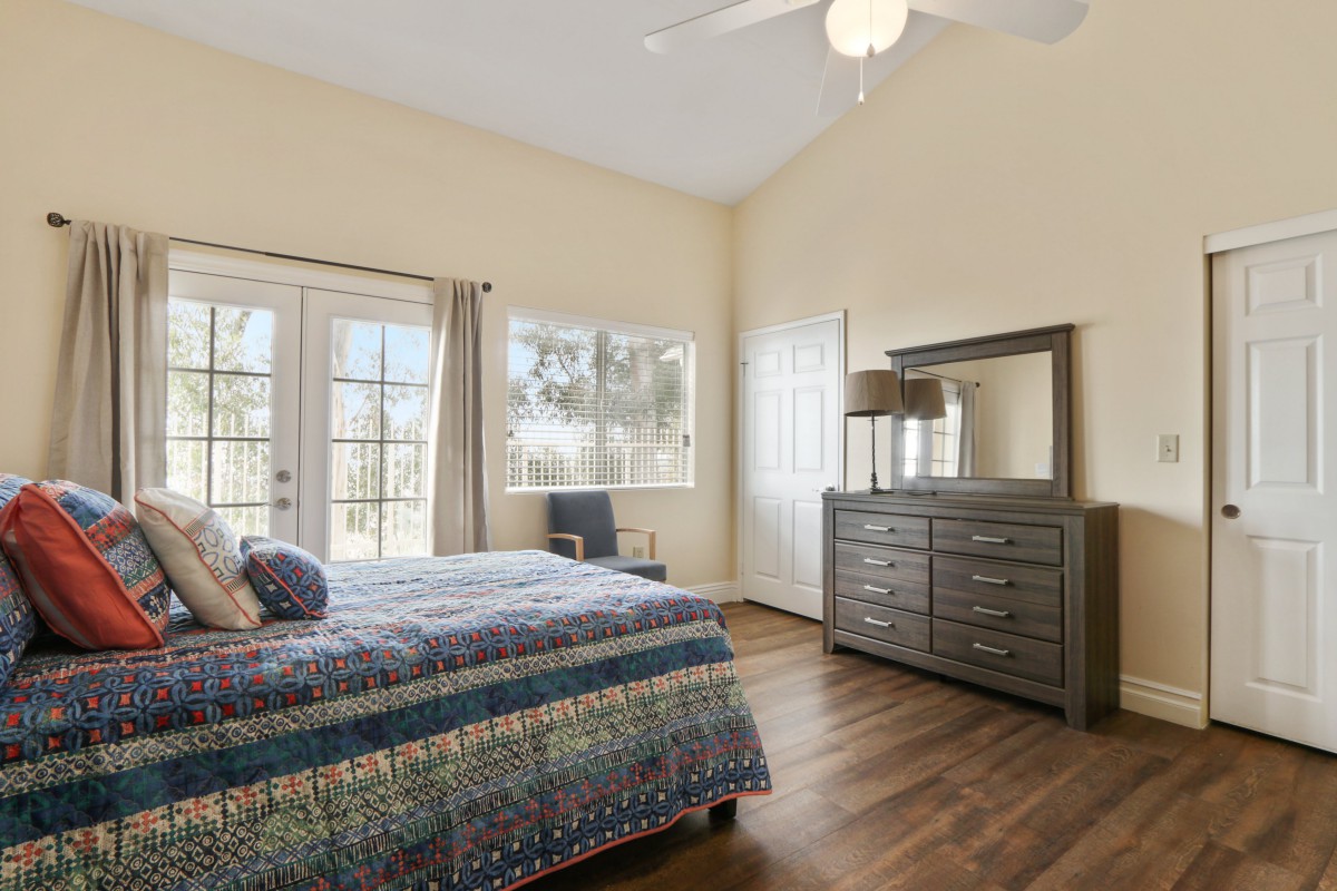 A well-lit bedroom with a large bed, dresser, and ceiling fan.