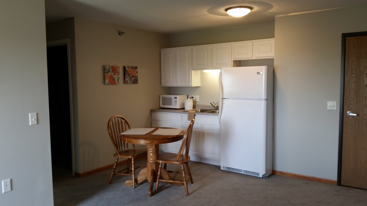 A small kitchen and dining area with a table, chairs, refrigerator, and microwave.