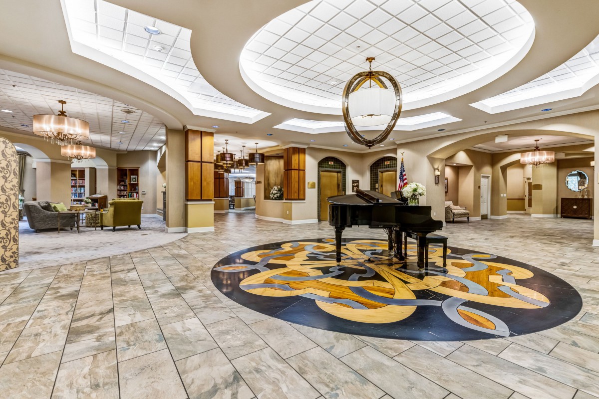 A luxurious hotel lobby with an elegant grand piano and a stunning chandelier.