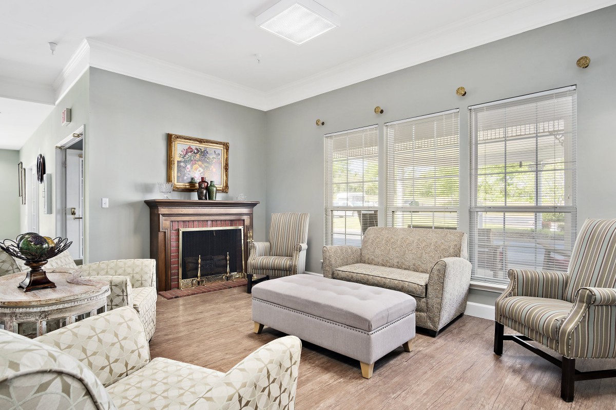 A cozy living room with modern furniture and a fireplace, featuring large windows that let in natural light.