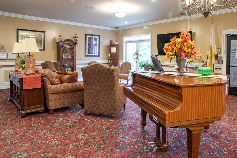 A cozy living room with comfortable seating, a piano, and elegant decor.