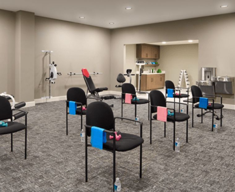 An empty waiting area in a clinic, organized with chairs and clipboards.